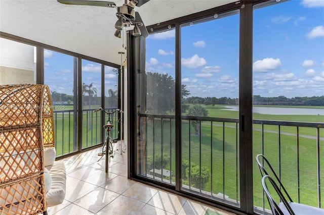 unfurnished sunroom featuring a wealth of natural light, a water view, and ceiling fan