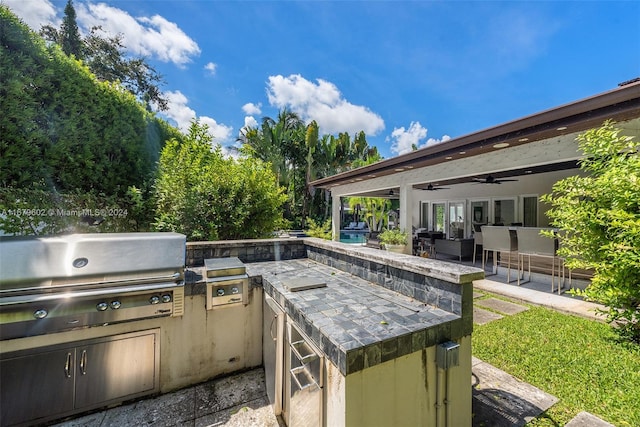 view of patio with ceiling fan, grilling area, and exterior kitchen