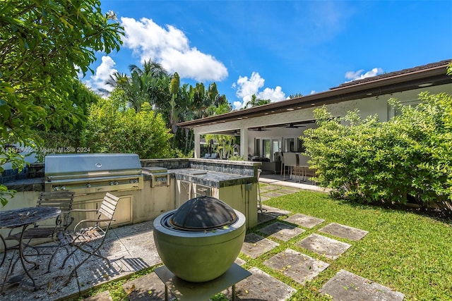 view of patio featuring exterior kitchen, a grill, and ceiling fan