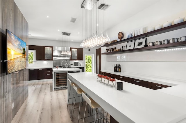 kitchen featuring wine cooler, a healthy amount of sunlight, a center island with sink, and hanging light fixtures