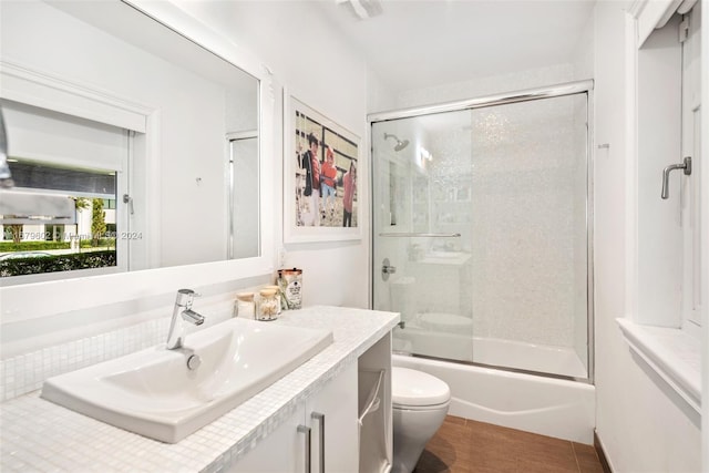 full bathroom featuring vanity, toilet, and shower / bath combination with glass door