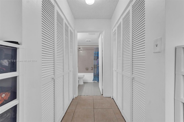 hall featuring a textured ceiling and light tile patterned floors