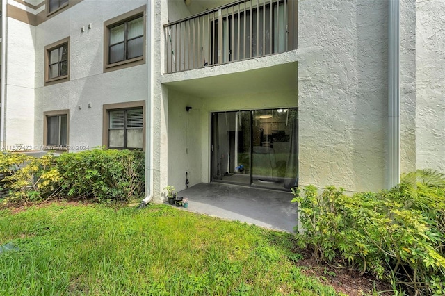 property entrance featuring a balcony, a yard, and a patio