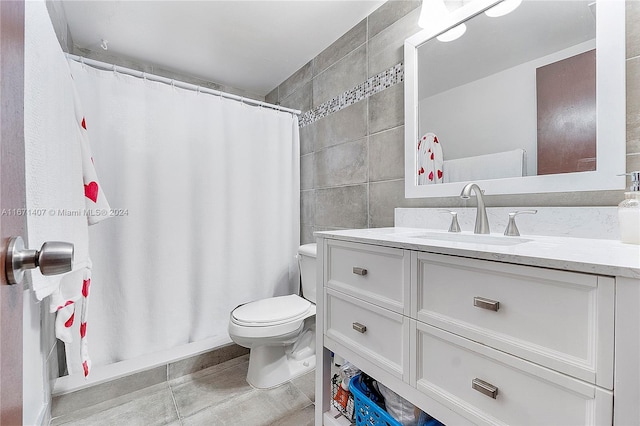 bathroom with curtained shower, toilet, tile walls, vanity, and tile patterned flooring