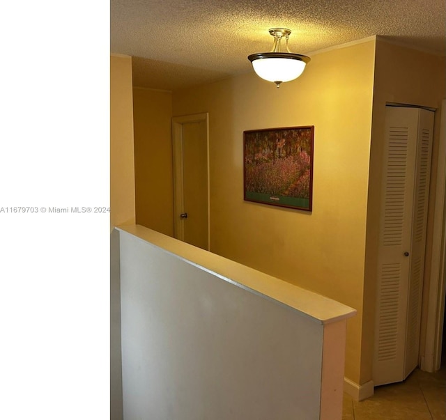 corridor featuring light tile patterned flooring and a textured ceiling