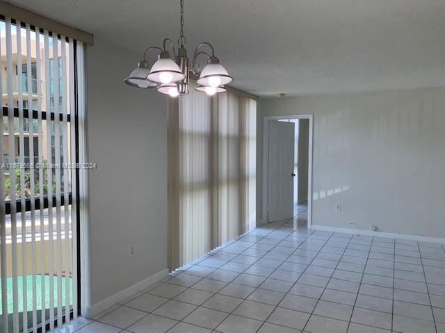 tiled empty room featuring a chandelier