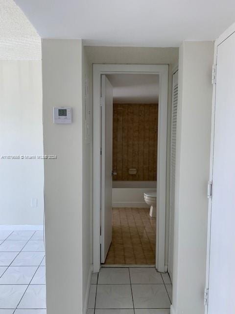 corridor with light tile patterned flooring and baseboards