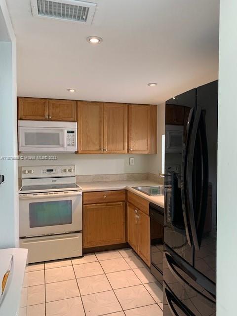 kitchen with black appliances, light countertops, light tile patterned floors, a sink, and recessed lighting