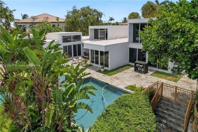 back of property with a patio, a fenced in pool, and a sunroom