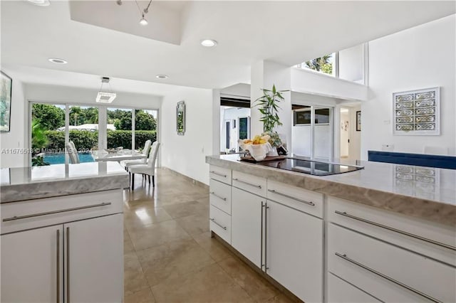 kitchen with a healthy amount of sunlight, light tile patterned floors, black electric cooktop, and white cabinets