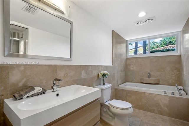 bathroom featuring tile walls, toilet, vanity, tiled bath, and tile patterned flooring