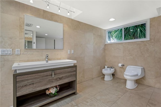 bathroom with tile walls, vanity, a bidet, and toilet