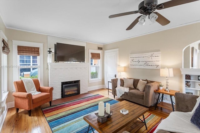 living area with a brick fireplace, crown molding, and wood finished floors