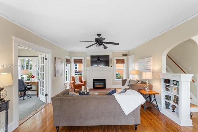 living room with light hardwood / wood-style flooring, ornamental molding, a fireplace, and ceiling fan