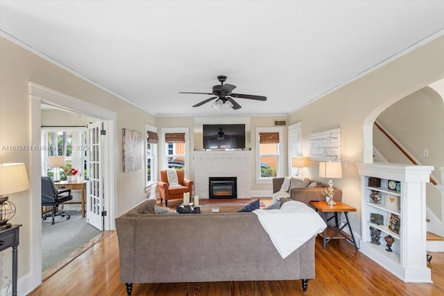 living area featuring stairs, light wood-style flooring, arched walkways, and a wealth of natural light