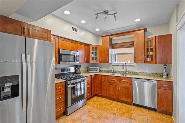 kitchen featuring stainless steel appliances, light stone countertops, and sink