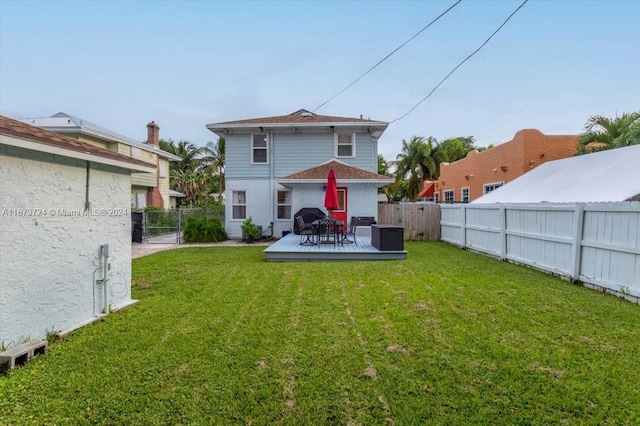 rear view of house featuring a wooden deck and a lawn