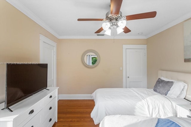 bedroom with dark wood-style floors, ornamental molding, a ceiling fan, and baseboards