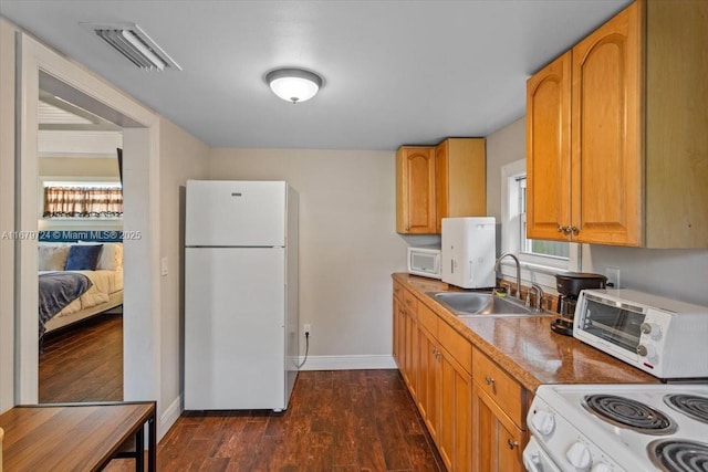 kitchen with dark wood-style floors, visible vents, a sink, white appliances, and baseboards