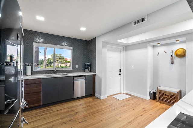 kitchen with sink, dark brown cabinetry, light hardwood / wood-style flooring, and dishwasher