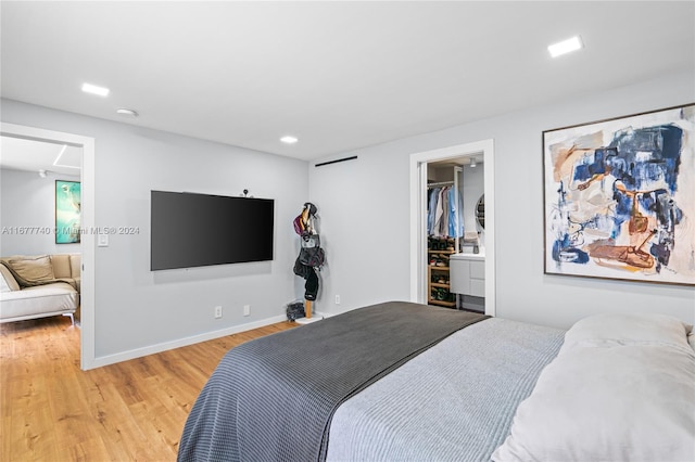 bedroom featuring light hardwood / wood-style flooring, a walk in closet, and a closet