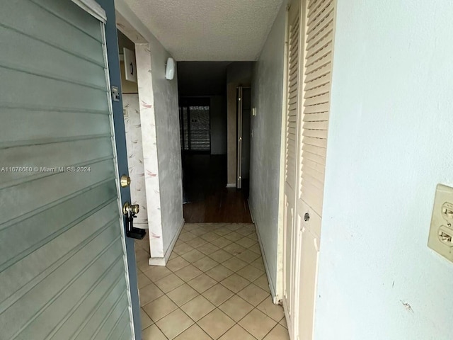 corridor with light tile patterned flooring and a textured ceiling