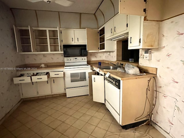 kitchen with light tile patterned flooring, white cabinetry, sink, and white appliances