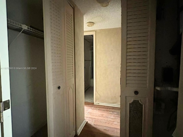 hallway with hardwood / wood-style flooring and a textured ceiling