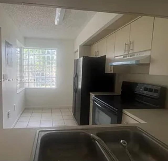 kitchen featuring electric range, sink, stainless steel fridge, cream cabinets, and a textured ceiling