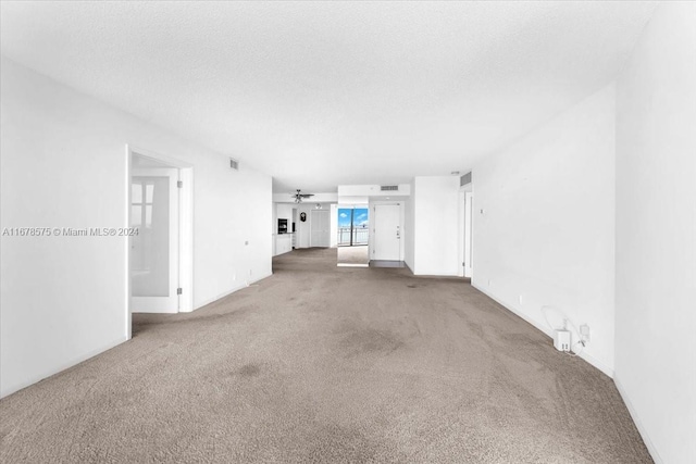 unfurnished living room featuring ceiling fan, carpet floors, and a textured ceiling