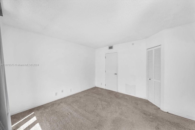 carpeted empty room with a textured ceiling