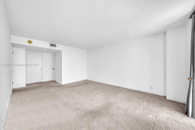 carpeted empty room featuring a textured ceiling