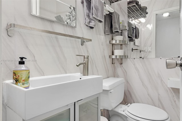 bathroom with vanity, toilet, and tile walls