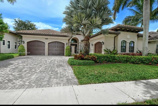 mediterranean / spanish house with a garage and a front lawn