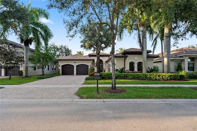 mediterranean / spanish-style home featuring a garage and a front lawn