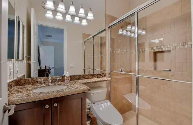 bathroom featuring toilet, a shower with shower door, and vanity