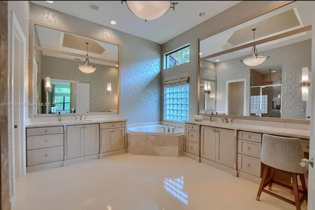 bathroom featuring vanity, a raised ceiling, and separate shower and tub