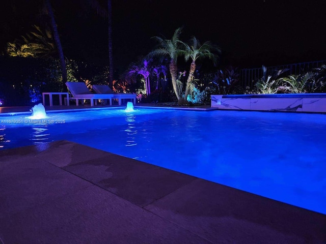 pool at twilight featuring pool water feature