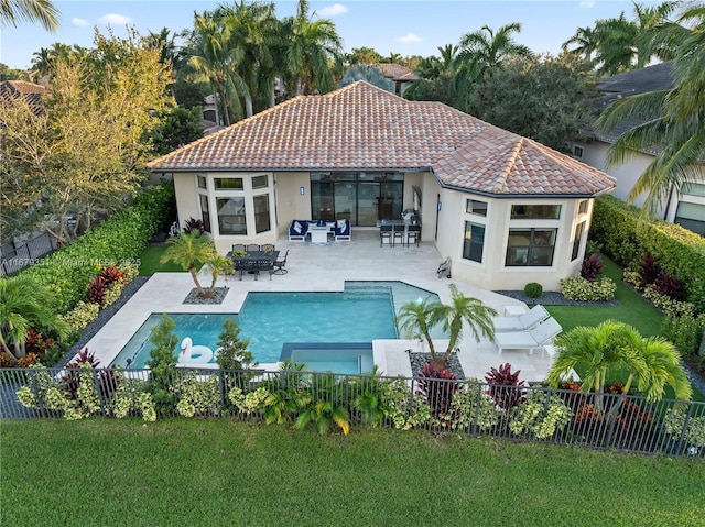 back of house with a fenced in pool, a patio, and a lawn