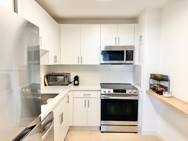 kitchen with light tile patterned flooring, white cabinetry, and stainless steel appliances