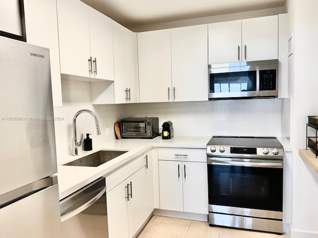 kitchen featuring white cabinetry, light tile patterned flooring, appliances with stainless steel finishes, and sink