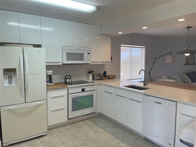 kitchen featuring white appliances, pendant lighting, white cabinetry, sink, and kitchen peninsula