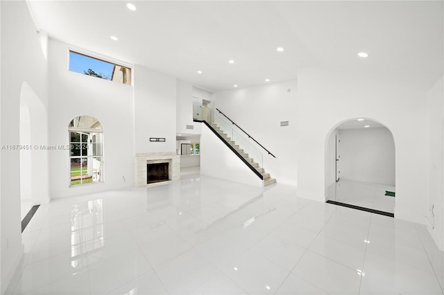 unfurnished living room with light tile patterned flooring and a high ceiling