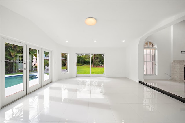 unfurnished living room featuring french doors, a stone fireplace, and light tile patterned floors