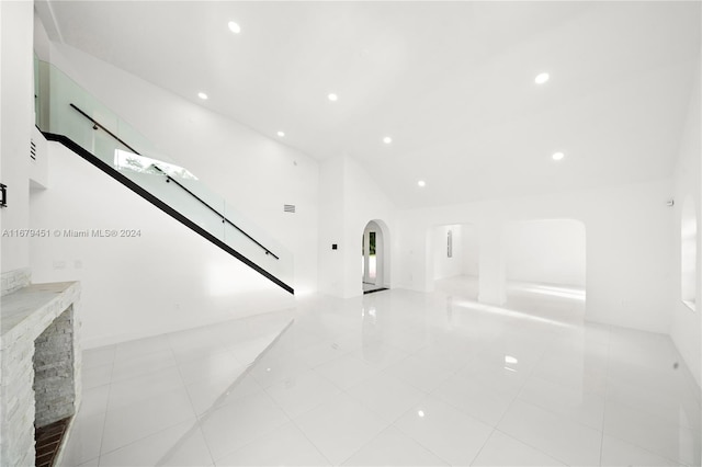 unfurnished living room with light tile patterned flooring, lofted ceiling, and a fireplace