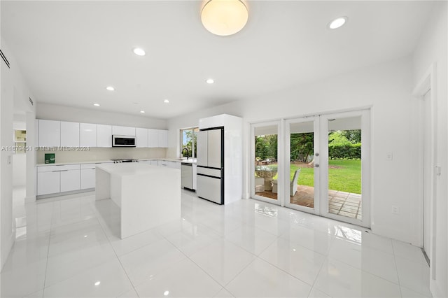 kitchen with sink, a center island, white cabinetry, stainless steel appliances, and light tile patterned floors