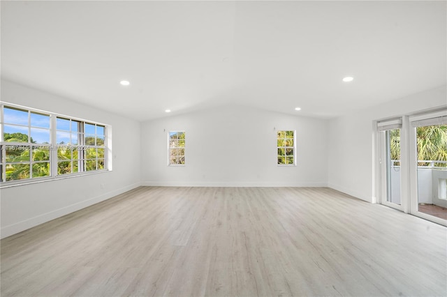 unfurnished room featuring vaulted ceiling, a healthy amount of sunlight, and light hardwood / wood-style flooring