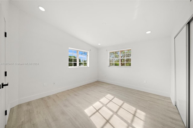 unfurnished bedroom featuring lofted ceiling, a closet, and light hardwood / wood-style floors