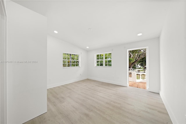 empty room featuring vaulted ceiling and light hardwood / wood-style floors