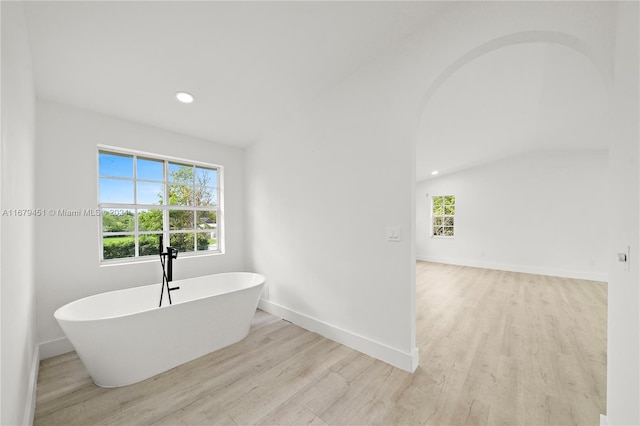 bathroom featuring a bathing tub, lofted ceiling, and hardwood / wood-style flooring